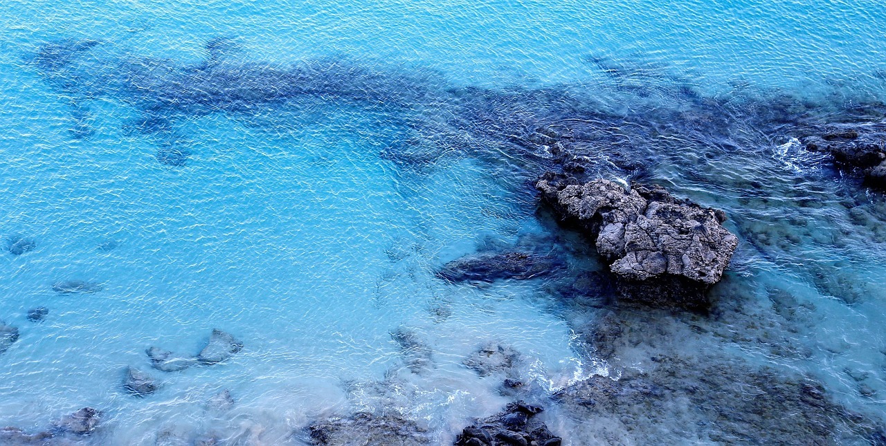 A blue water with rocks
AI-generated content may be incorrect.