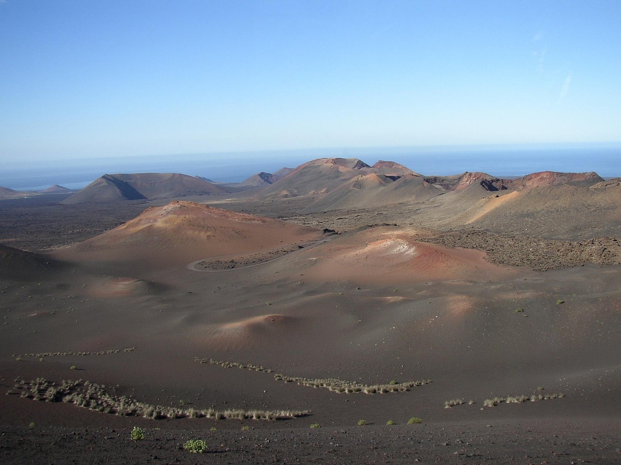 A landscape of a desert with Timanfaya National Park in the background
AI-generated content may be incorrect.