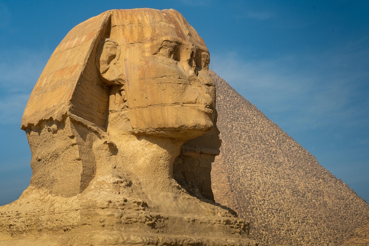 A statue of a person in front of a pyramid with Great Sphinx of Giza in the background
AI-generated content may be incorrect.