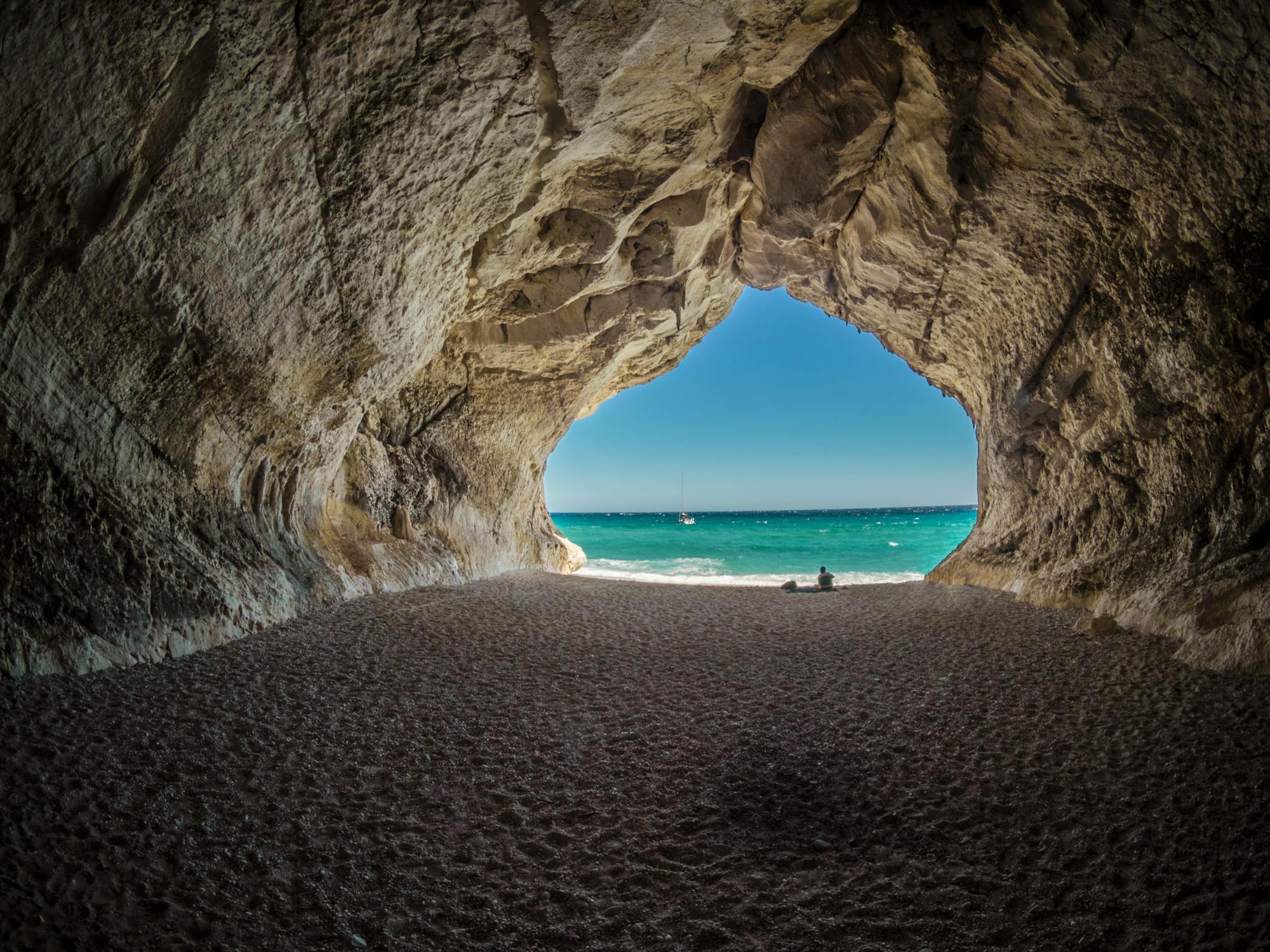 A cave with a beach and blue water

AI-generated content may be incorrect.